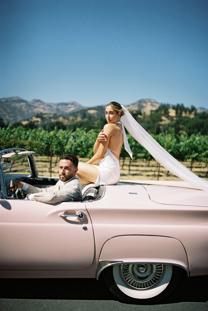 Bride and groom portraits in vintage pink convertible